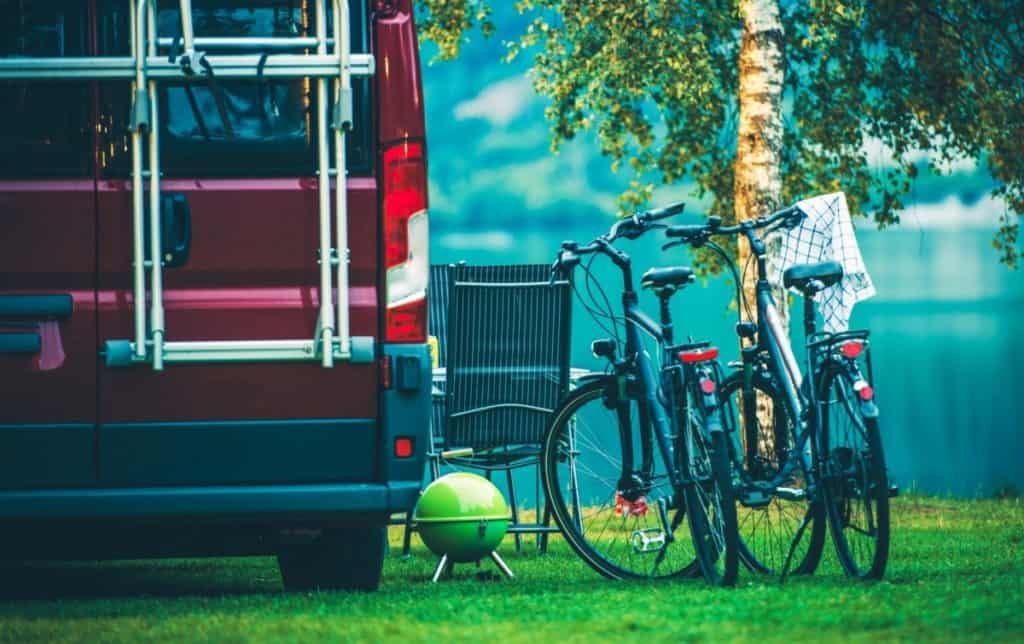 RV Camper Camping and Biking. Motorcoach and Two Bikes on the Campsite.